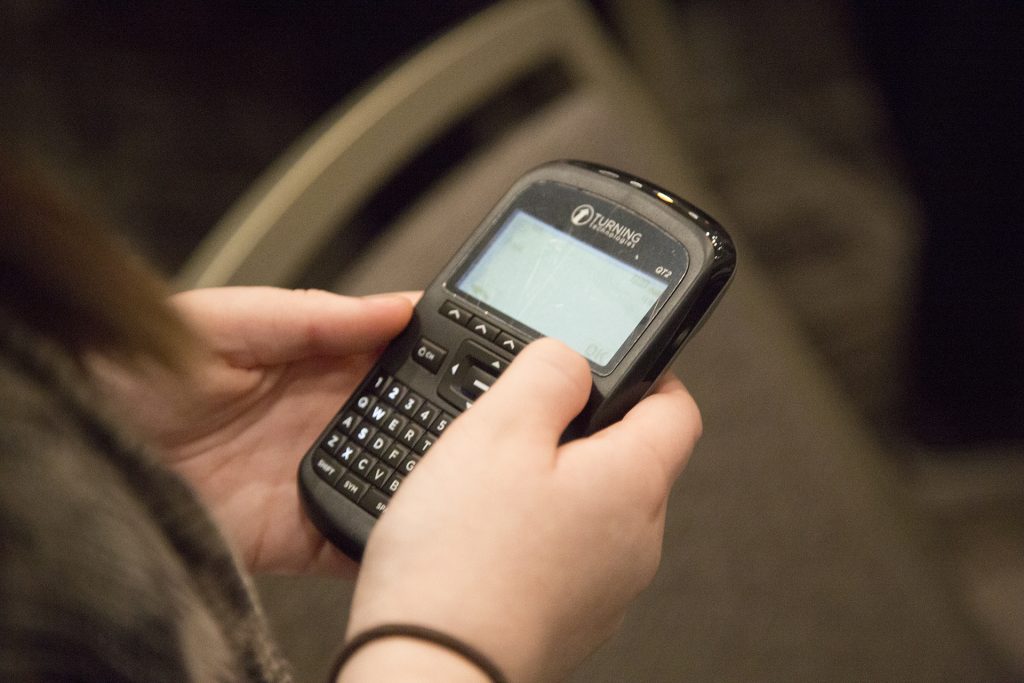 A closeup of a handheld electronic voting device, held by two hands