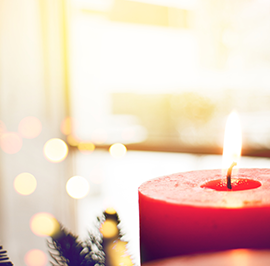 Advent, Christmas, and Holiday Services in the Diocese of Olympia An Advent candle in the foreground, with a sunlit window and Christmas lights in the background.