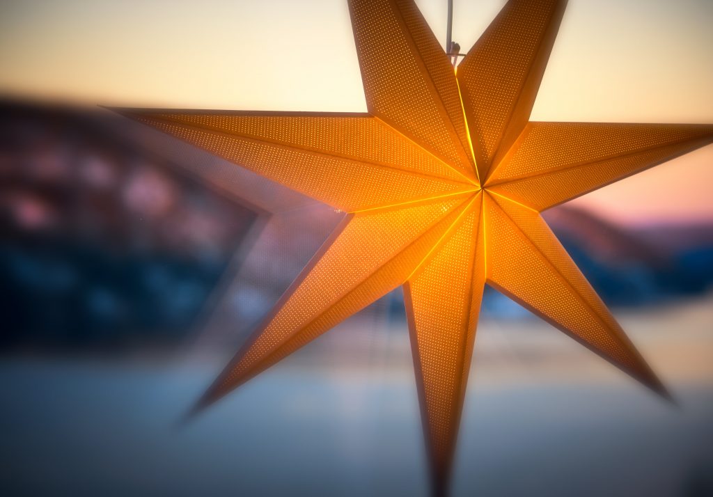 A brown paper star, hanging and illuminated by a light